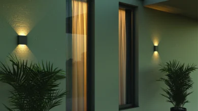 Fachada de uma casa com parede pintada de verde, duas arandelas pretas e dois vasos de plantas.