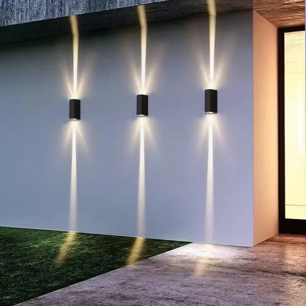 Muro externo com três arandelas retangulares pretas.