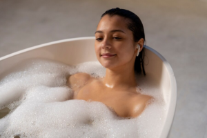 Mulher de fones de ouvido em uma banheira com água e espuma.