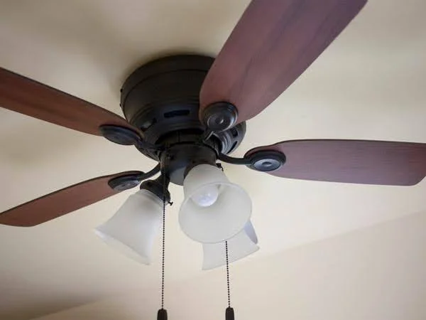 Ventilador de teto com acionamento de cordão de 4 pás e 3 luminárias visto de baixo.
