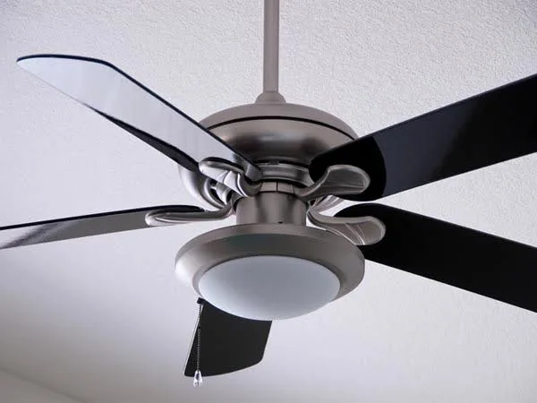 Ventilador de teto de 5 pás e uma luminária branca visto de baixo.