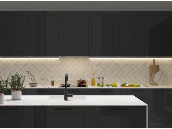 Cozinha com móveis pretos, parede com revestimento branco e fitas de LED abaixo dos armários superiores posicionados acima da bancada.