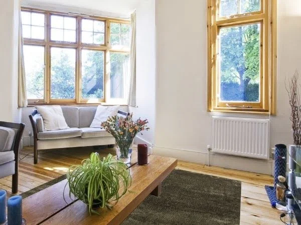 Sala de estar decorada com sofás cinzas, móveis e janelas de madeira