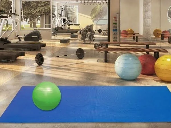 Sala de academia com um tapete de yoga azul em destaque.
