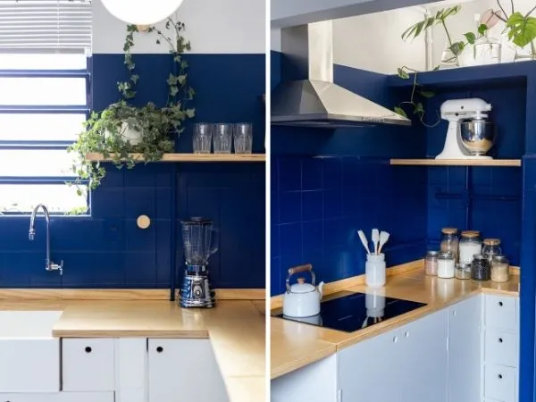 Parede de uma cozinha pintada de azul com uma bancada nas cores branca e amadeirada.