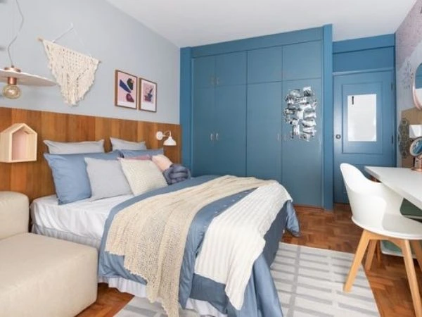 Quarto azul-claro com parede azul em tom mais escuro com armário embutido e porta na mesma cor.