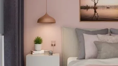 Pintura para quarto rosa-claro, e cama com roupa de cama cinza e rosa clara.