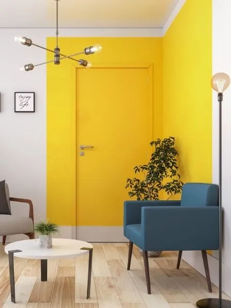 Pintura para sala branca com cubo amarelo pintado cobrindo a porta de entrada.