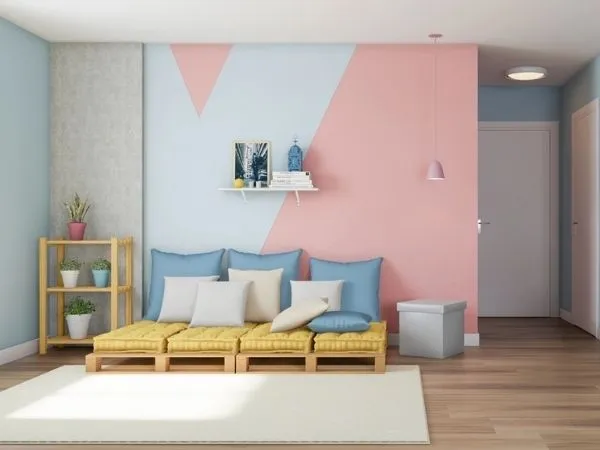 Sala azul com parede com pallets e almofadas na cor rosa e formato “V” em azul.