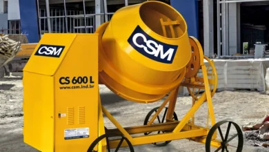 Betoneira amarela modelo CS 600L da marca CSM em um canteiro de obras, posicionada em frente a uma construção.