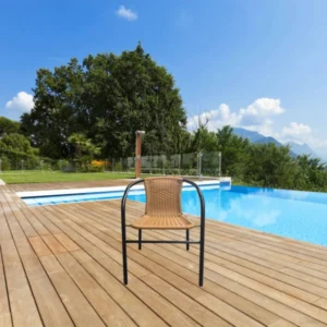 Cadeira de fibra sintética e aço em um deck de madeira com uma piscina ao fundo.