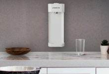 Purificador de parede branco instalado em uma cozinha cinza acima de uma bancada branca.