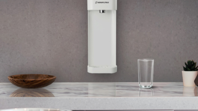 Purificador de parede branco instalado em uma cozinha cinza acima de uma bancada branca.
