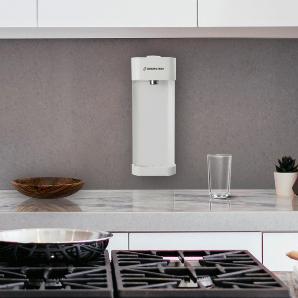 Purificador de parede branco instalado em uma cozinha cinza acima de uma bancada branca.