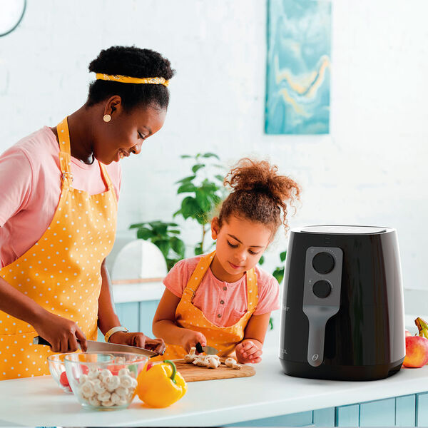 Air fryer Oster 3 3L 127V ao lado de mãe e filha cozinhando