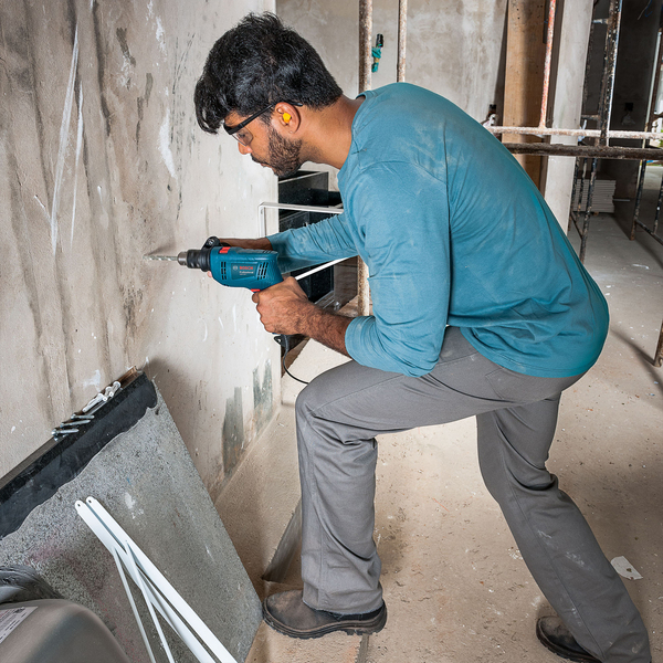Ferramentas para eletricista: Furadeira de Impacto Bosch com Chave de Mandril e Acessórios 550W sendo utilizado em obra