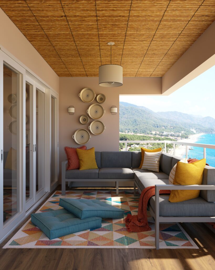 Sacada com vista para o mar, contendo um sofá de canto com almofadas, um tapete colorido e enfeites circulares na parede.