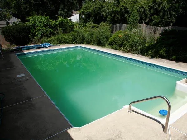Piscina em área externa com água verde.
