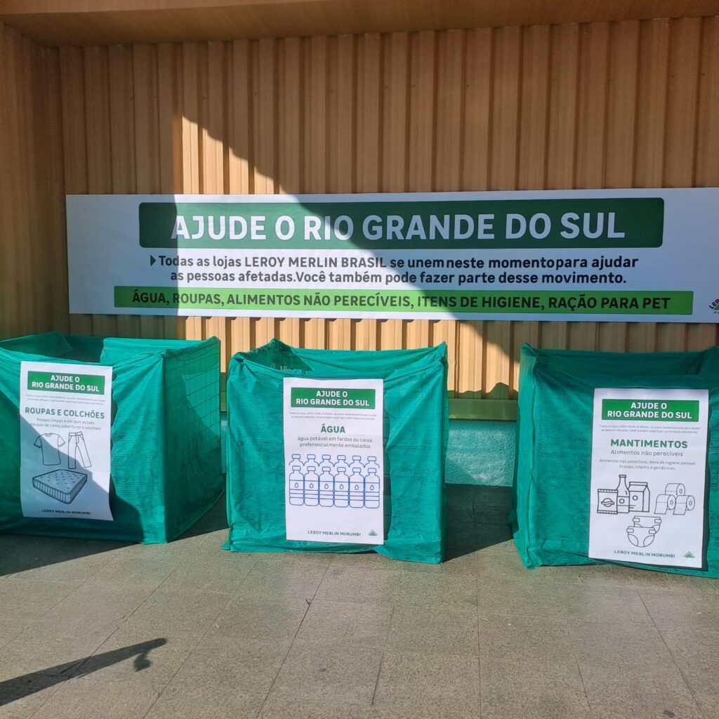 Caixas verdes de arrecadação de doações para o Rio Grande do Sul, com uma faixa acima falando sobre a campanha de arrecadação feita pela Leroy Merlin.
