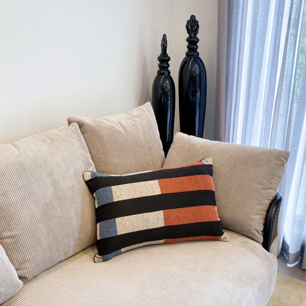 Sofá com almofada nas cores laranja, azul, branco e preto.