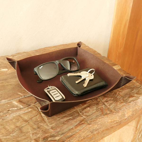 Bandeja porta objetos com óculos, chaves e carteira dentro dela.