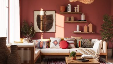 Sala com paredes vermelhas, sofá e mesa de centro de madeira, contendo almofadas coloridas e outros acessórios no estilo de decoração boho.