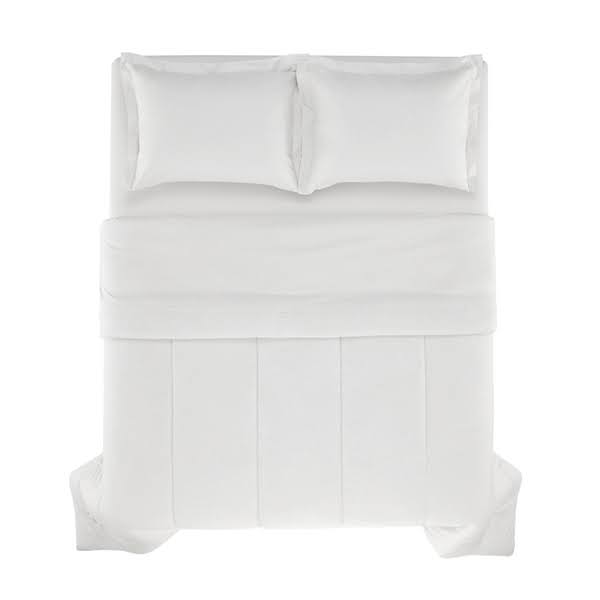 Imagem de uma cama de casal coberta por um edredom branco.