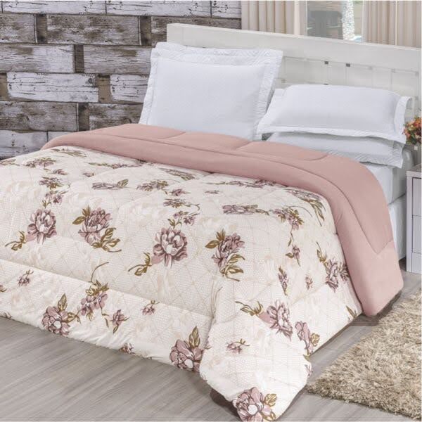 Imagem de uma cama de casal coberta por um edredom e lençóis de cor clara e estampados com flores.