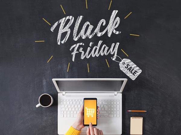 Imagem de uma pessoa utilizando um celular e um computador. Em destaque está escrito “Black Friday”.