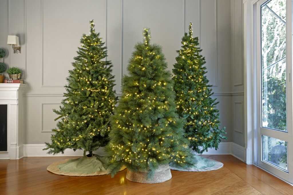 Sala de estar com três árvores de Natal enfeitadas com piscas-piscas.
