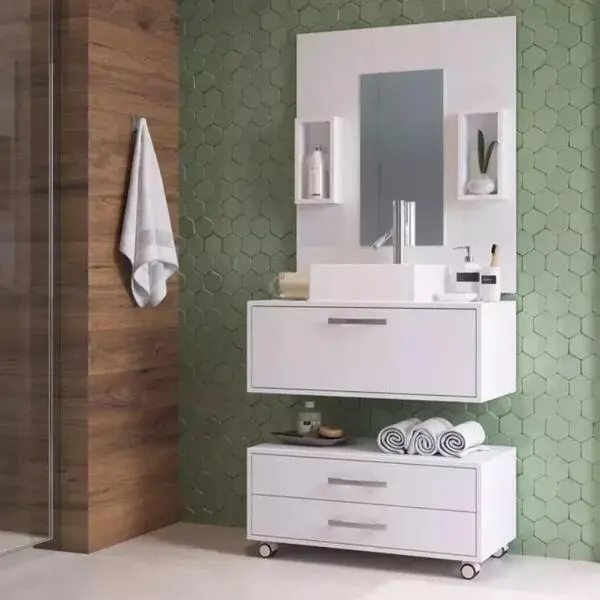 Banheiro com revestimento erde e conjunto de gabinete com cuba e painel balcão branco.