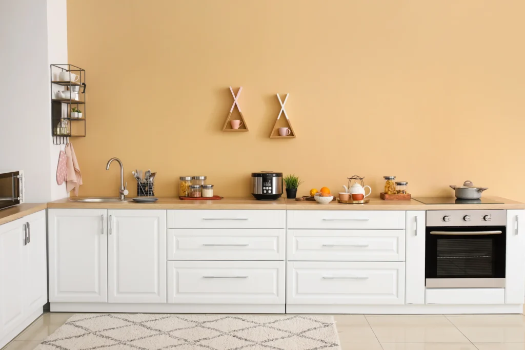 Bancada de cozinha de cores claras e decorada com potes herméticos, alimentos e panelas.