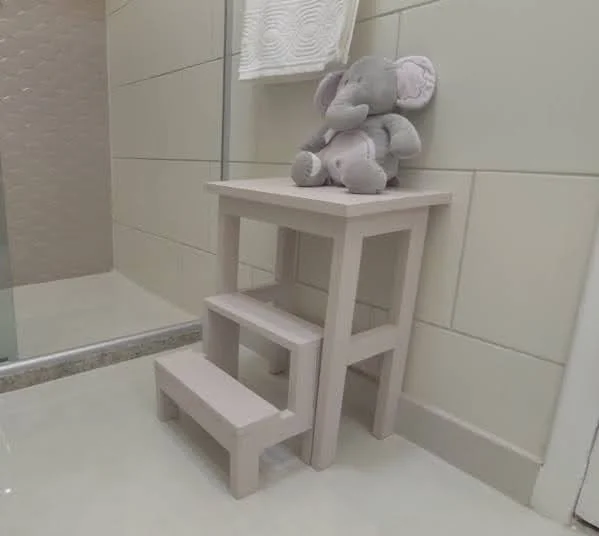 Banco com degraus em um banheiro com um elefante de pelúcia sobre ele.
