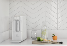 Purificador de água branco instalado em uma bancada de cozinha de clores claras.