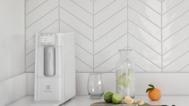 Purificador de água branco instalado em uma bancada de cozinha de clores claras.