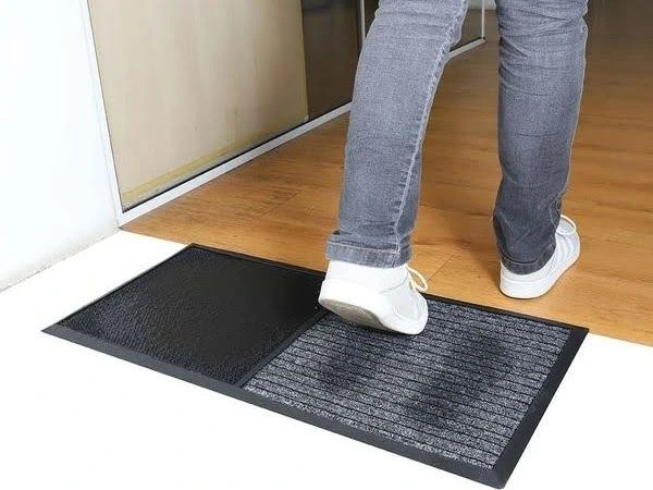 Pessoa pisando em um tapete sanitizante preto.